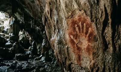 Detalhe de uma arte rupestre mais antiga do mundo, uma estêncil de mão pré-histórica de 67.800 anos com formato de garra, gravada em uma parede de caverna de ca