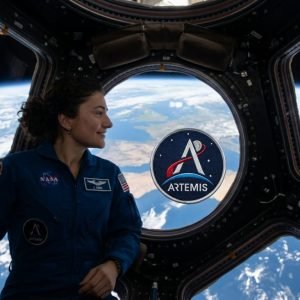 Astronauta Jessica Meir na Estação Espacial Internacional com patch Artemis II, simbolizando o caminho para o retorno à Lua.