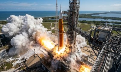 Simulação visual do lançamento do foguete SLS da missão Artemis II, mostrando a interação da pluma de exaustão com o sistema de supressão de som na plataforma de lançamento.