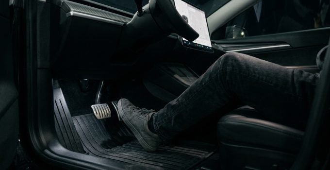 Pé de motorista sobre o pedal do acelerador de um Tesla, ilustrando a tecnologia de condução com um pedal da Tesla e a discussão sobre aceleração inesperada.