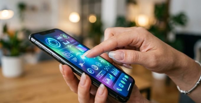 Mão com unhas longas e esmalte condutor transparente interagindo facilmente com a tela sensível ao toque de um smartphone, demonstrando a inovação da tecnologia