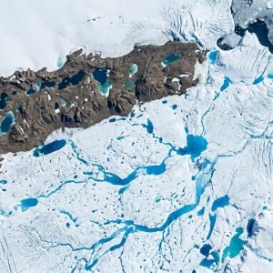 Vista aérea dos lagos de degelo azuis na Antártida, com canais de água derretida sobre a plataforma de gelo Nivlisen, um sinal do aquecimento global.