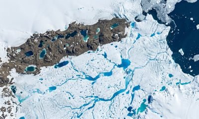 Vista aérea dos lagos de degelo azuis na Antártida, com canais de água derretida sobre a plataforma de gelo Nivlisen, um sinal do aquecimento global.