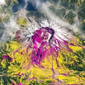 Imagem de radar capturada pela Missão NISAR do Monte Santa Helena, revelando detalhes da superfície através das nuvens, com áreas coloridas indicando vegetação.