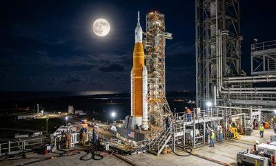 A Lua brilhando sobre o foguete SLS e a nave Orion, elementos cruciais da Política Espacial Nacional NASA, enquanto equipes se preparam para o ensaio geral de l