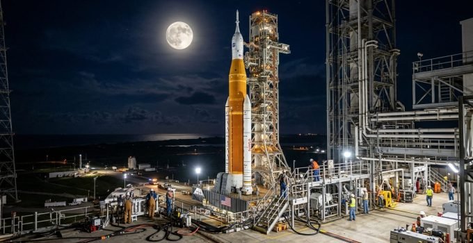 A Lua brilhando sobre o foguete SLS e a nave Orion, elementos cruciais da Política Espacial Nacional NASA, enquanto equipes se preparam para o ensaio geral de l