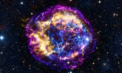 Imagem composta da Supernova RCW 86, destacando a borda externa em roxo (IXPE), raios-X de baixa energia em amarelo e de alta energia em azul, sobre um campo es