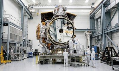 O Telescópio Espacial Nancy Grace Roman, completo e imponente, é visto dentro de uma sala limpa da NASA, com técnicos ao fundo, pronto para futuras descobertas.